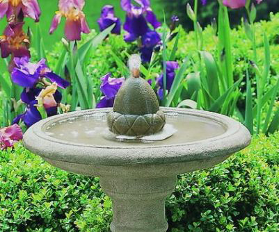 stone acorn bird bath fountain in flower garden