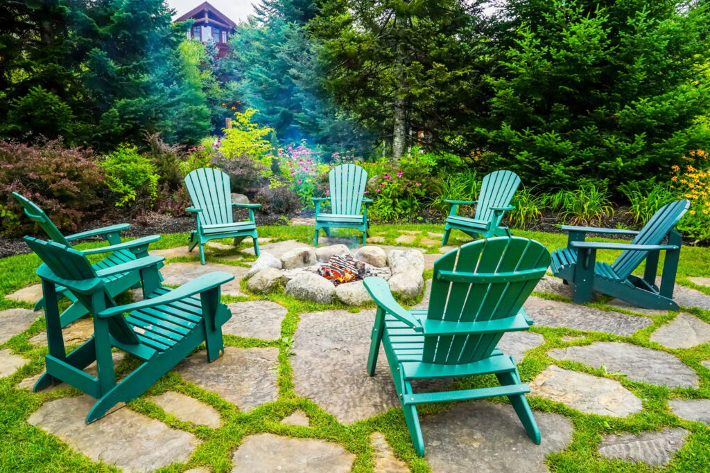 well-landscaped fire pit area with green chairs surrounding it