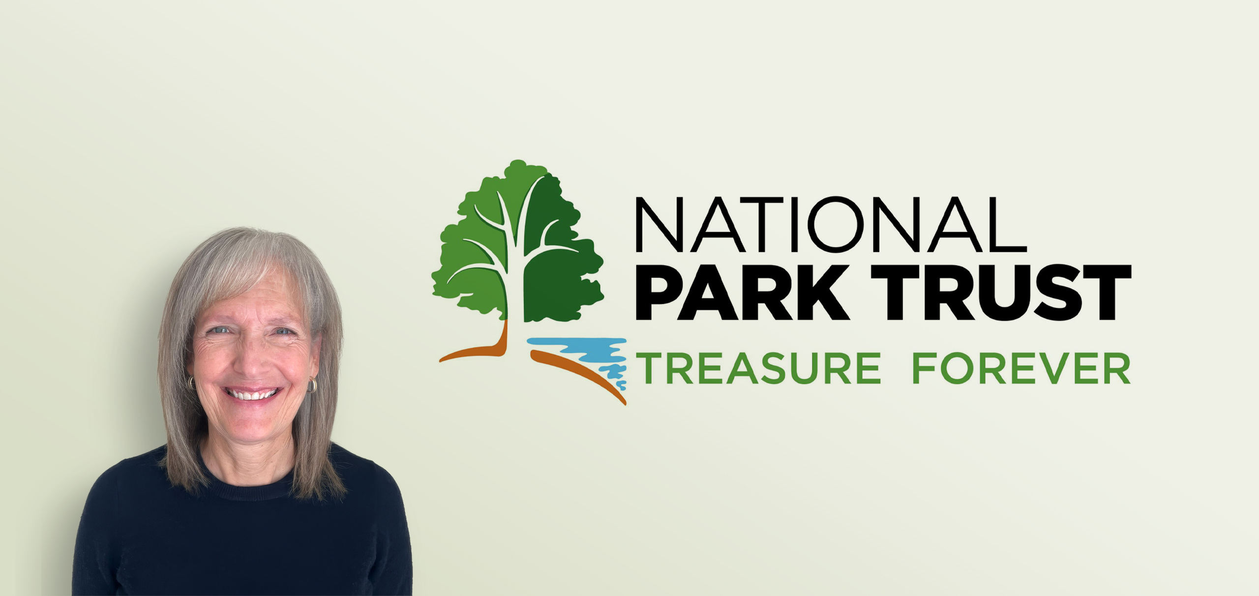Lisa Stadler smiling in front of the National Park Trust logo